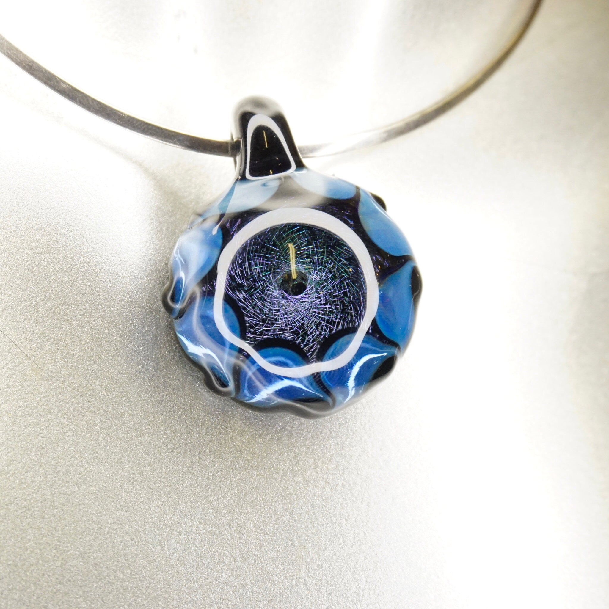 Blue and black artisan glass pendant with abstract light fractal designs, modernist jewelry style, worn on a black cord necklace