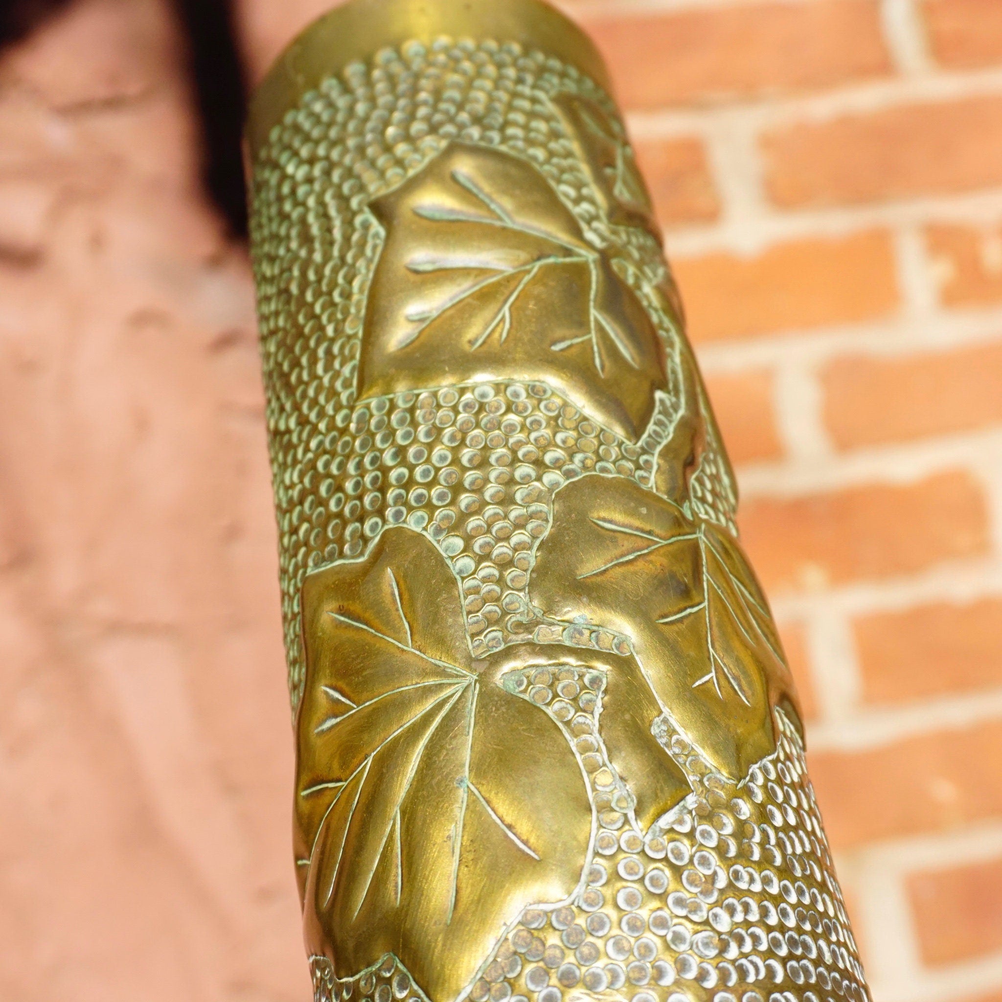 Antique French brass shell casing from 1917 repurposed as a decorative brush holder, featuring an intricate etched leaf design, a piece of trench art from World War I.