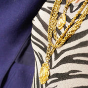 Vintage gold tone layered chain necklace with six strands and two ornate gold pendants against zebra print fabric