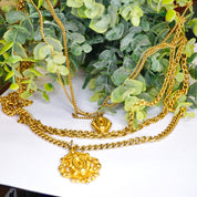 Vintage gold tone multi-strand chain necklace with pendants on greenery background