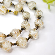 Vintage Italian Murano glass wedding cake bead choker necklace with clear and white beads strung on gold tone chain, closeup view on white background