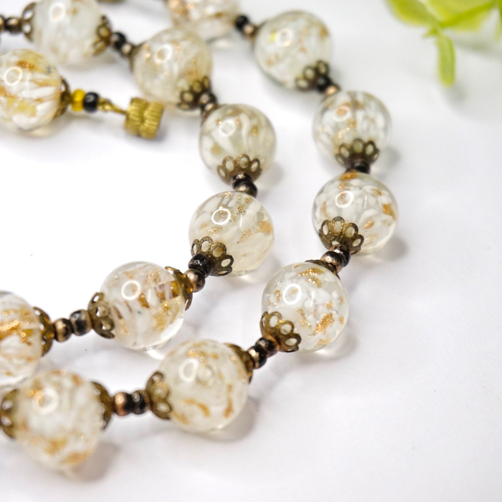 Vintage Italian Murano glass wedding cake bead choker necklace with clear and white beads strung on gold tone chain, closeup view on white background