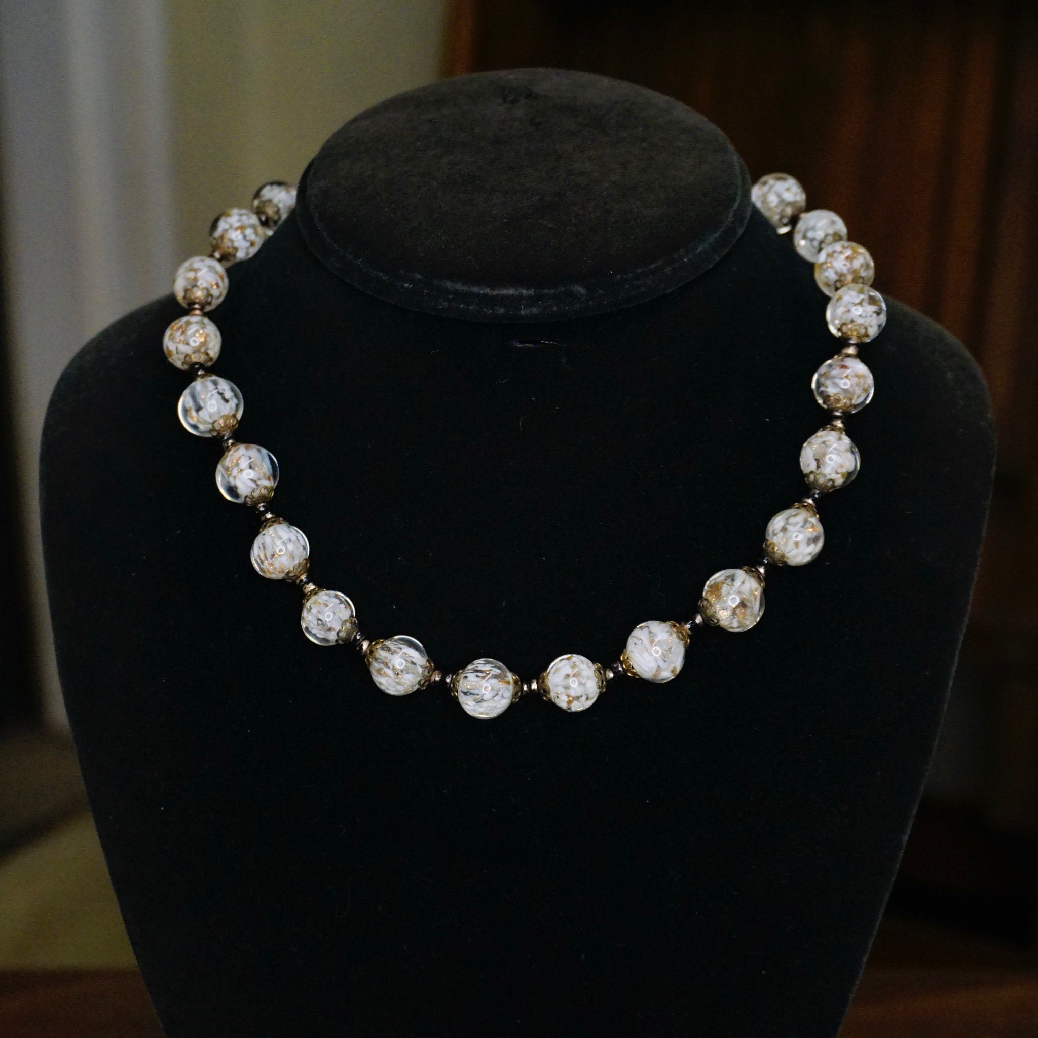 Vintage Italian Murano glass bead choker necklace with clear and white wedding cake style beads displayed on a black jewelry stand.