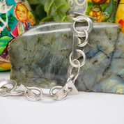 Vintage Taxco sterling silver link bracelet with modern geometric shapes on marbled stone background with colorful Russian nesting dolls in background.