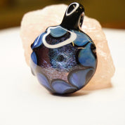 Retro glass pendant with abstract blue and black swirl design, handmade artisan jewelry featuring light fractals and modernist style.