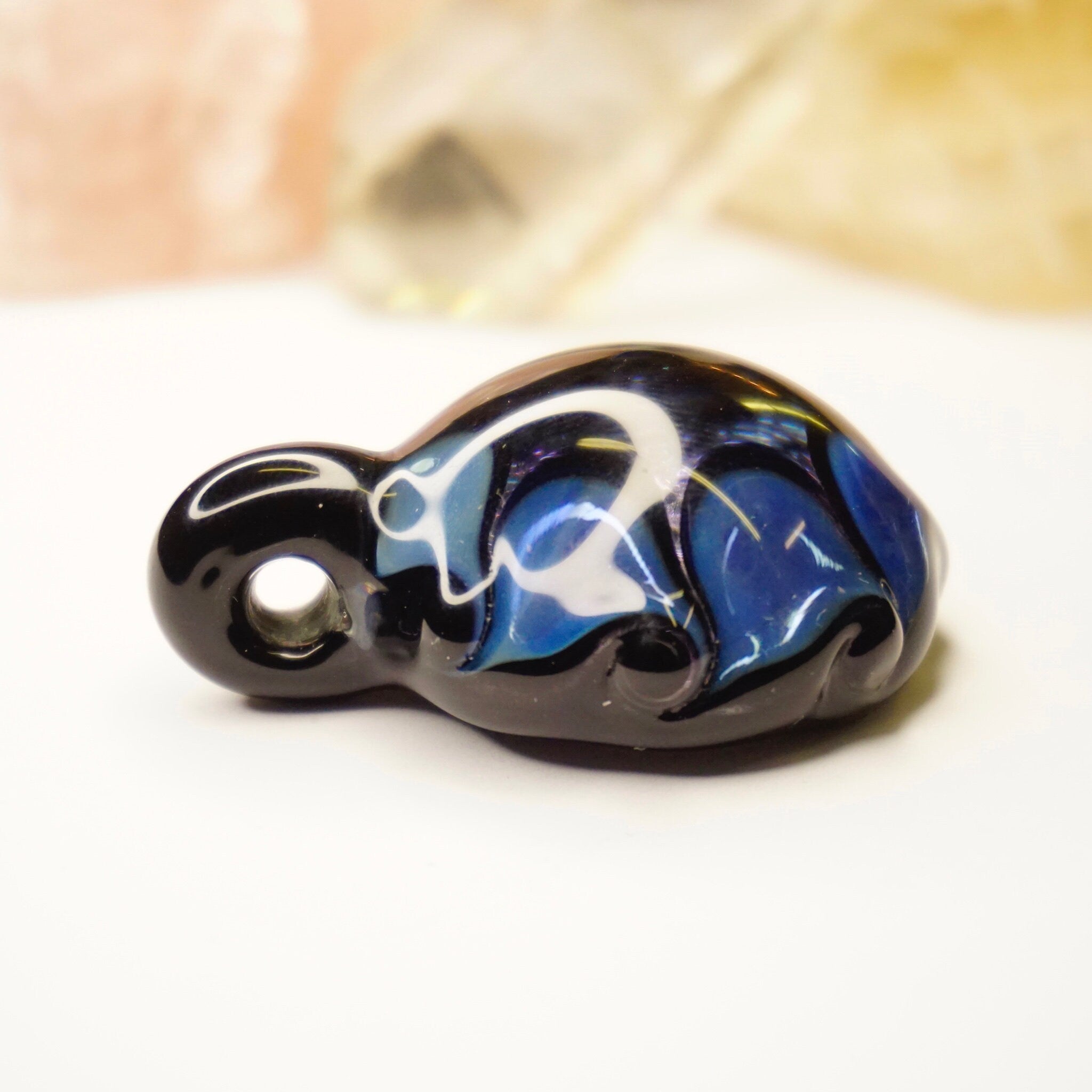 Retro glass pendant with abstract blue and black swirled design, displaying light fractals. Artisan crafted modernist jewelry piece.