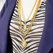 Vintage gold tone layered chain necklace with zebra print top and navy blue blazer, featuring multiple strands and two ornate pendants