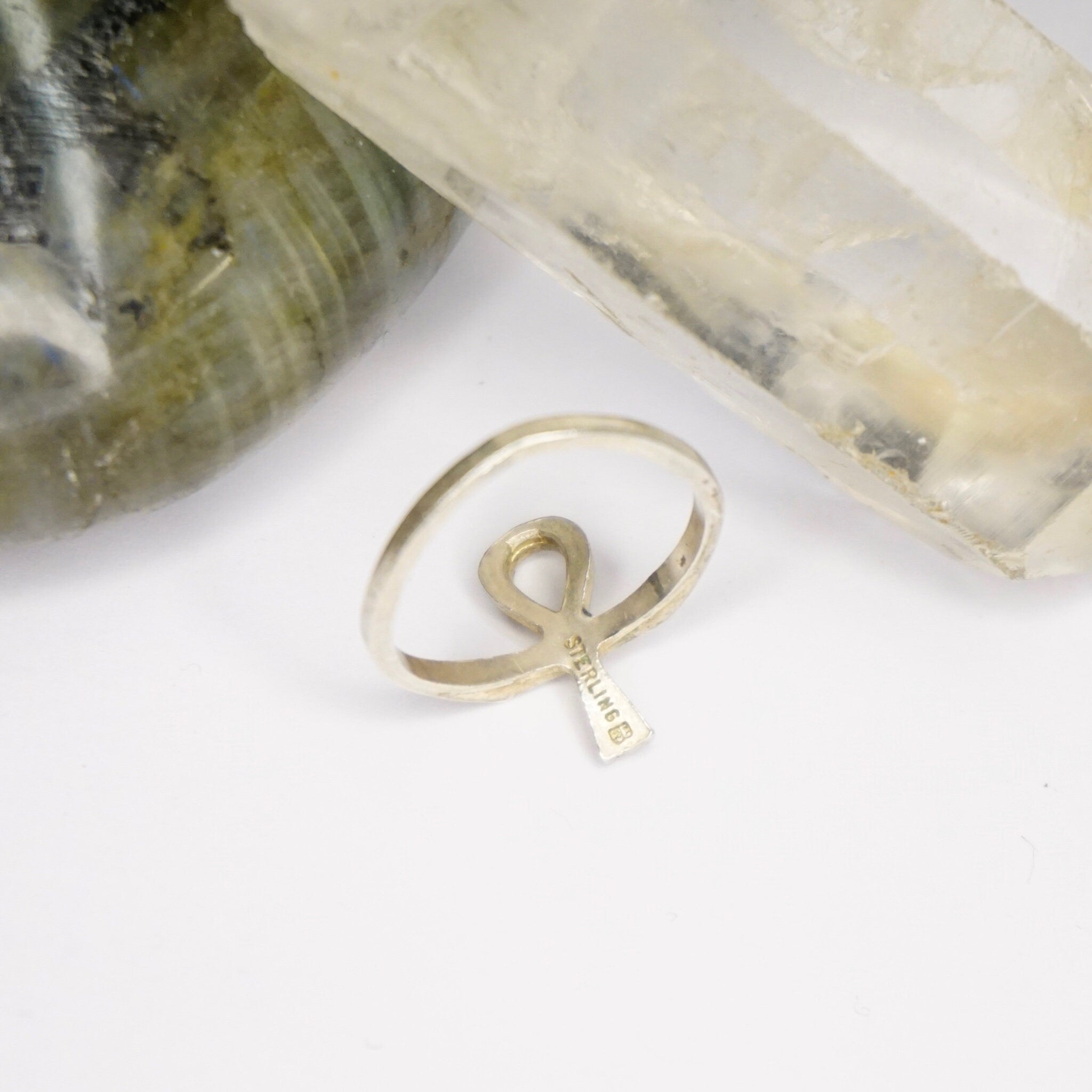 Vintage sterling silver Ankh ring featuring the Egyptian cross symbol on a thin band, displayed on a white background with crystals.