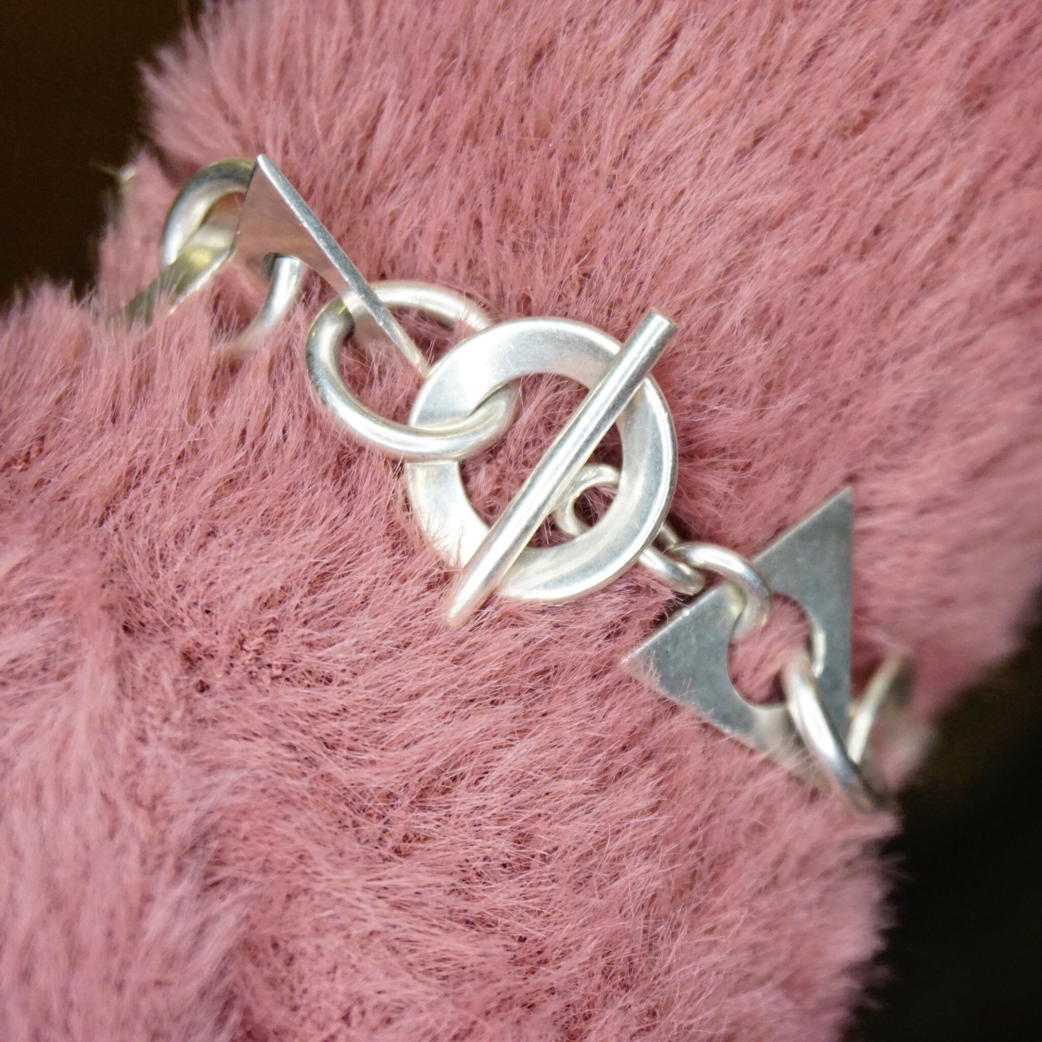 Vintage sterling silver link bracelet with geometric shapes and toggle clasp, handcrafted Taxco 925 silver jewelry from Mexico, shown on pink fur background.