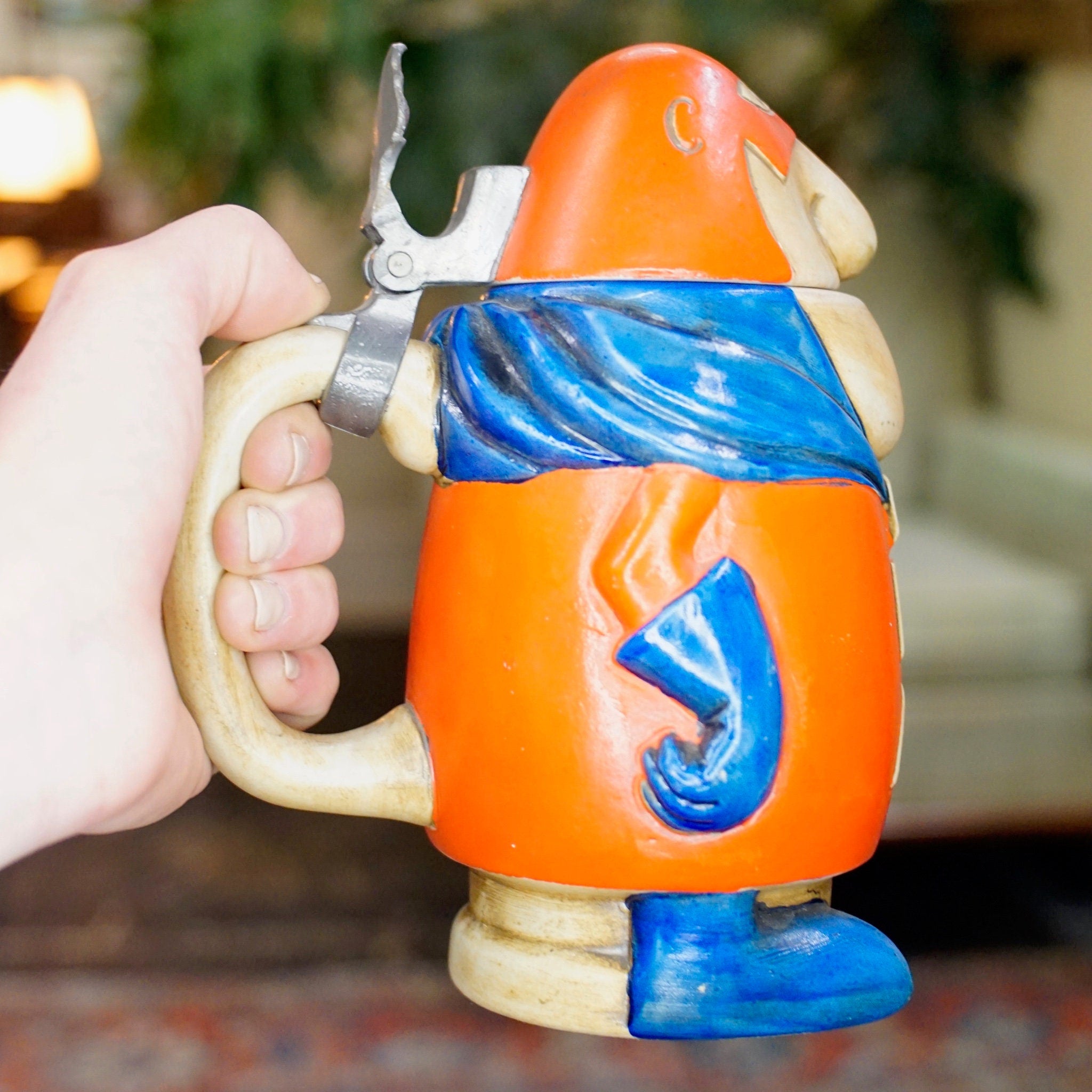 Vintage Anheuser Busch Bud Man ceramic beer stein figurine with orange body and blue legs, holding a silver wrench, made by Ceramarte in Brazil in 1975.