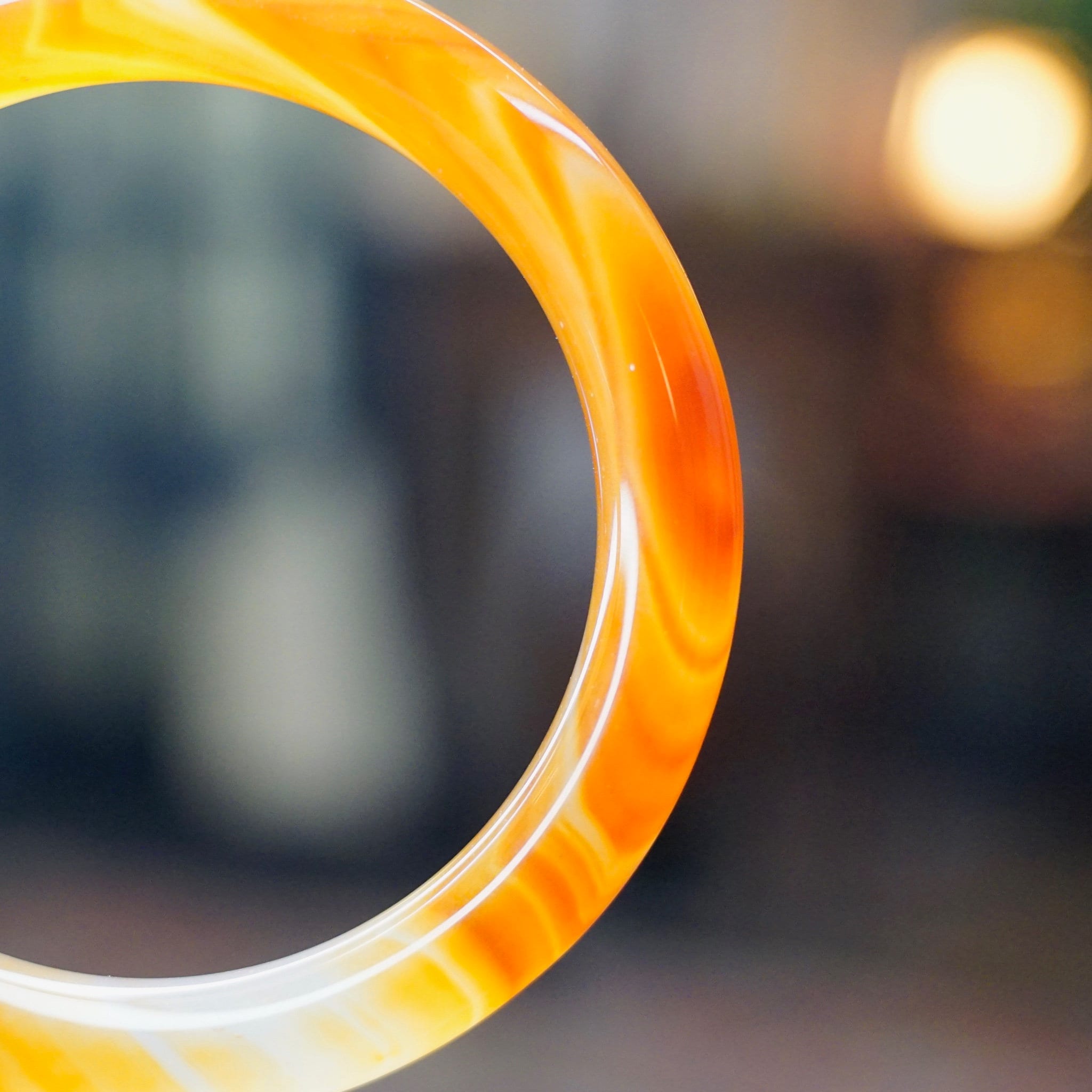 Vintage 1960's Venetian Murano glass bangle featuring a marbled orange and yellow semi-translucent design with colorful swirls, photographed with a blurred background.