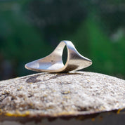Vintage sterling silver lightning bolt ring on stone surface with blurred green foliage background
