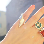 Vintage sterling silver lightning bolt ring with elongated points on a hand, featuring a small turquoise stone charm on the ring finger.