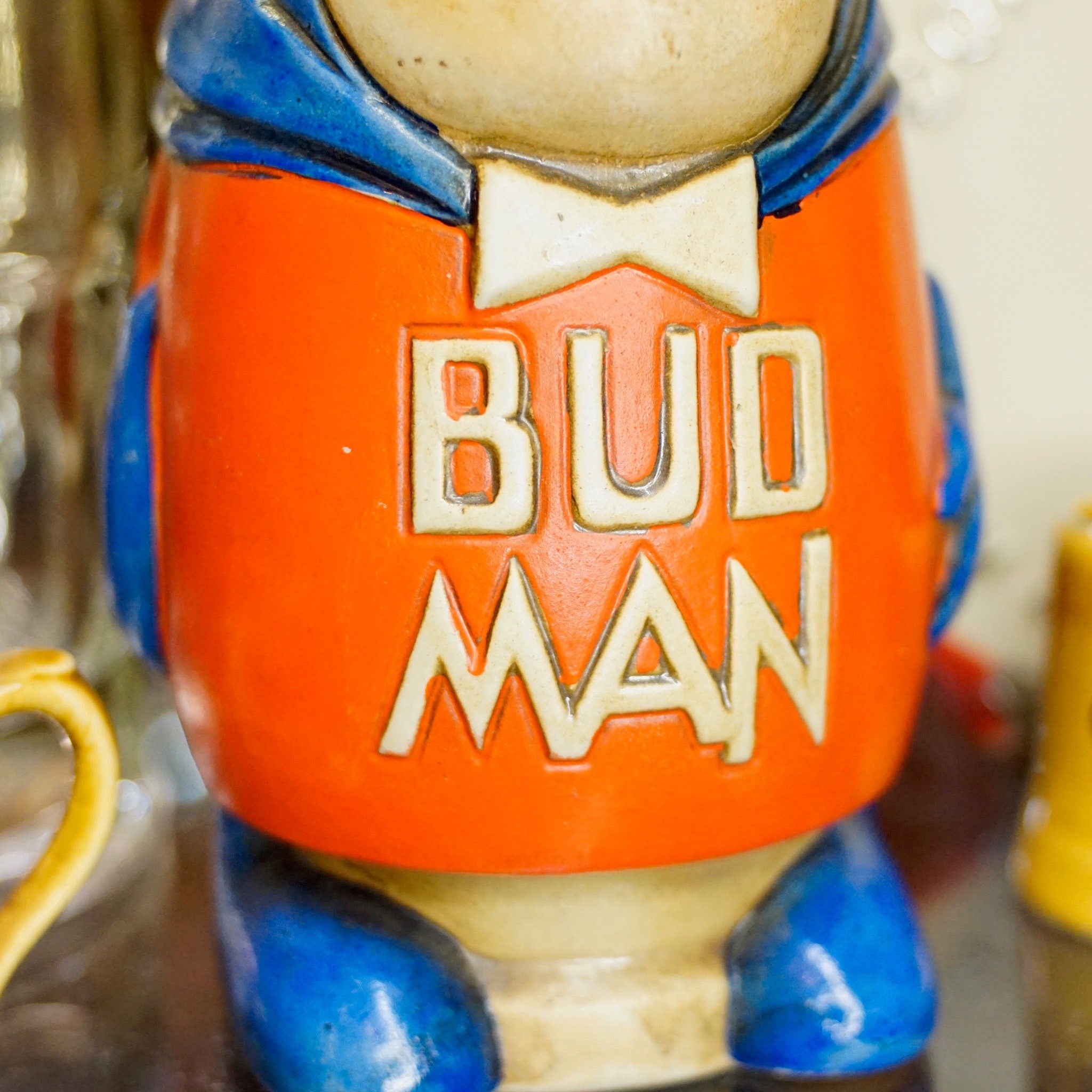 Vintage 1975 Anheuser Busch Bud Man beer stein figurine, orange and blue ceramic collectible stein made by Ceramarte in Brazil, debut Bud Man character design on display.