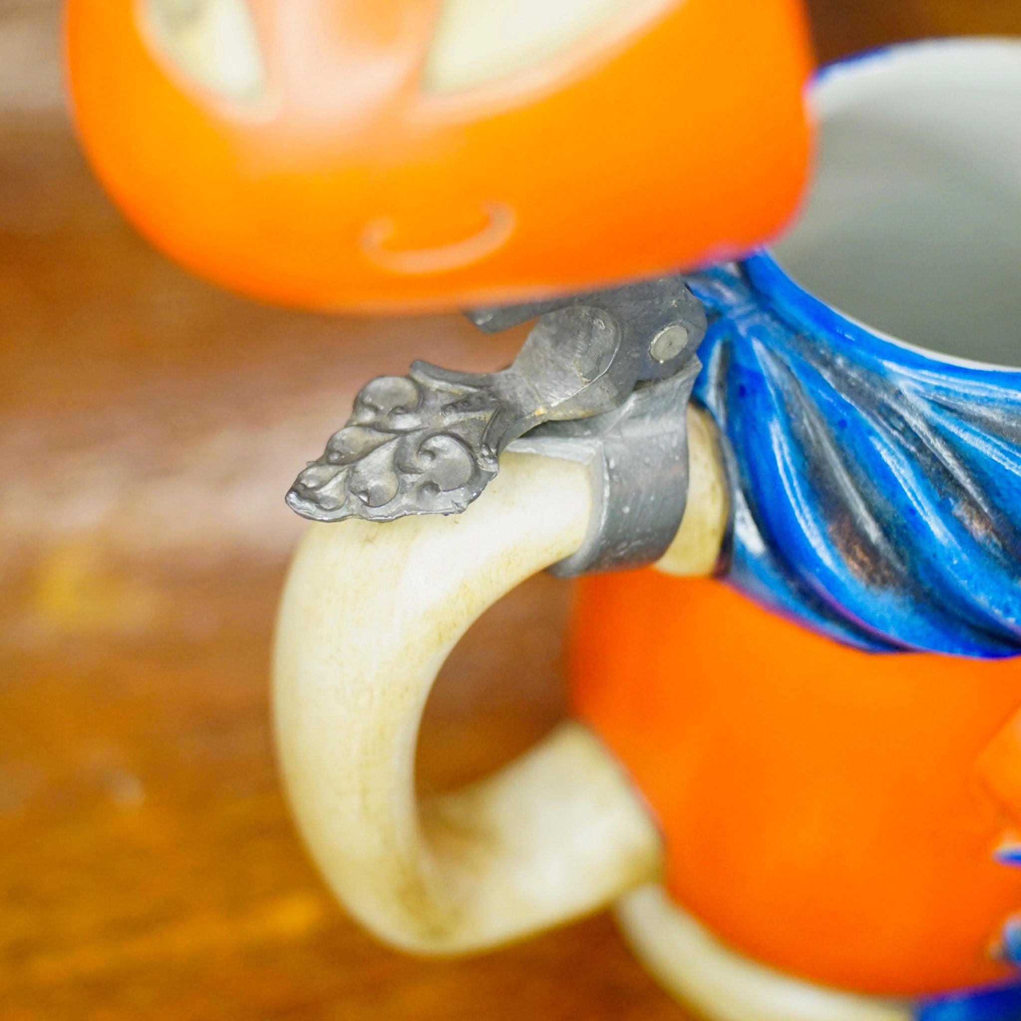 Vintage 1975 Anheuser Busch Bud Man ceramic beer stein made in Brazil by Ceramarte, featuring the debut collectible Bud Man figurine perched on the handle of an orange mug.