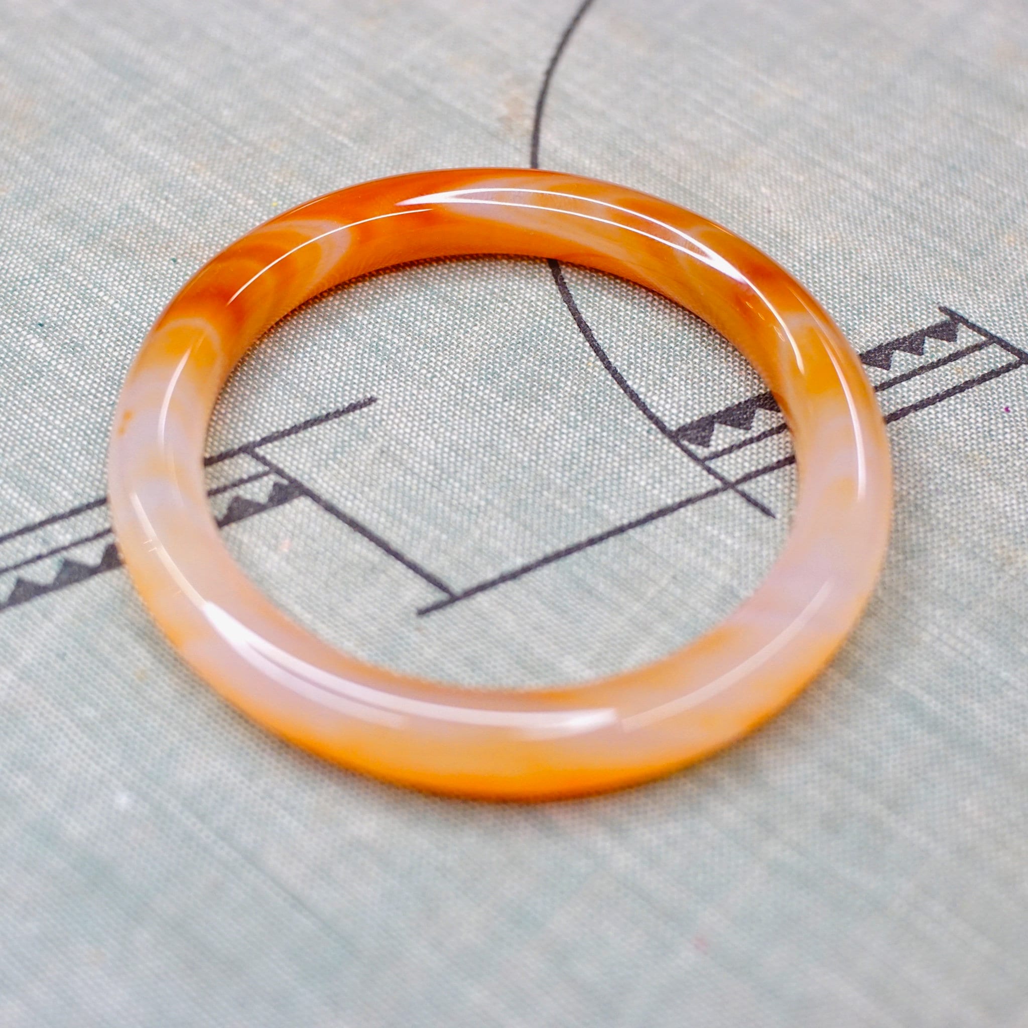 Vintage 1960's Murano glass bangle featuring marbled orange and white semi-translucent swirl design on neutral fabric background