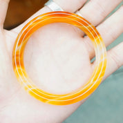 Vintage 1960's orange Murano glass bangle bracelet with marbled semi-translucent swirl design held in hand
