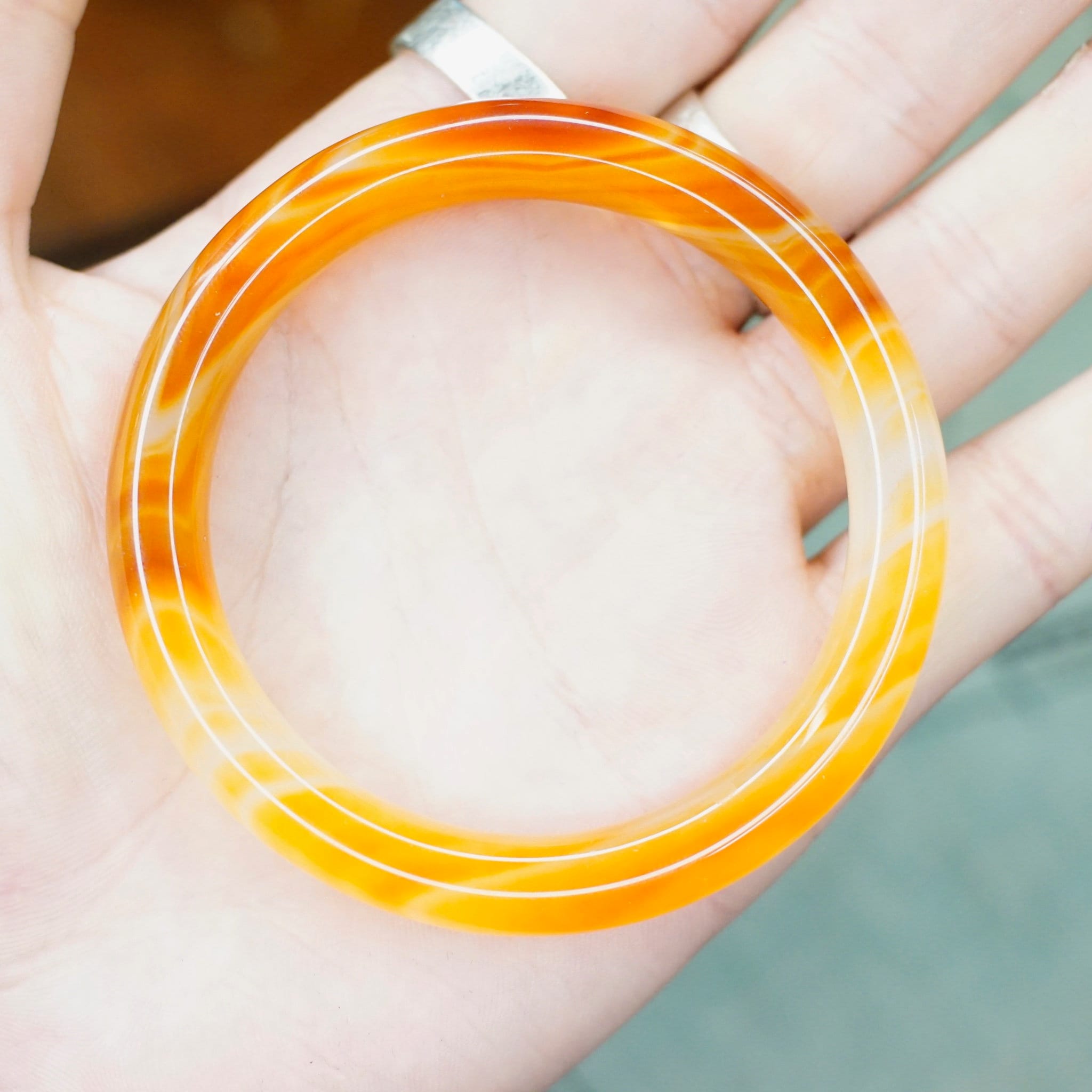Vintage 1960's orange Murano glass bangle bracelet with marbled semi-translucent swirl design held in hand