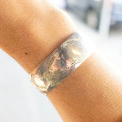 Vintage sterling silver cuff bracelet with etched floral design on wrist, close-up view showing intricate engraved details on the silver cuff with space for monogram initials.