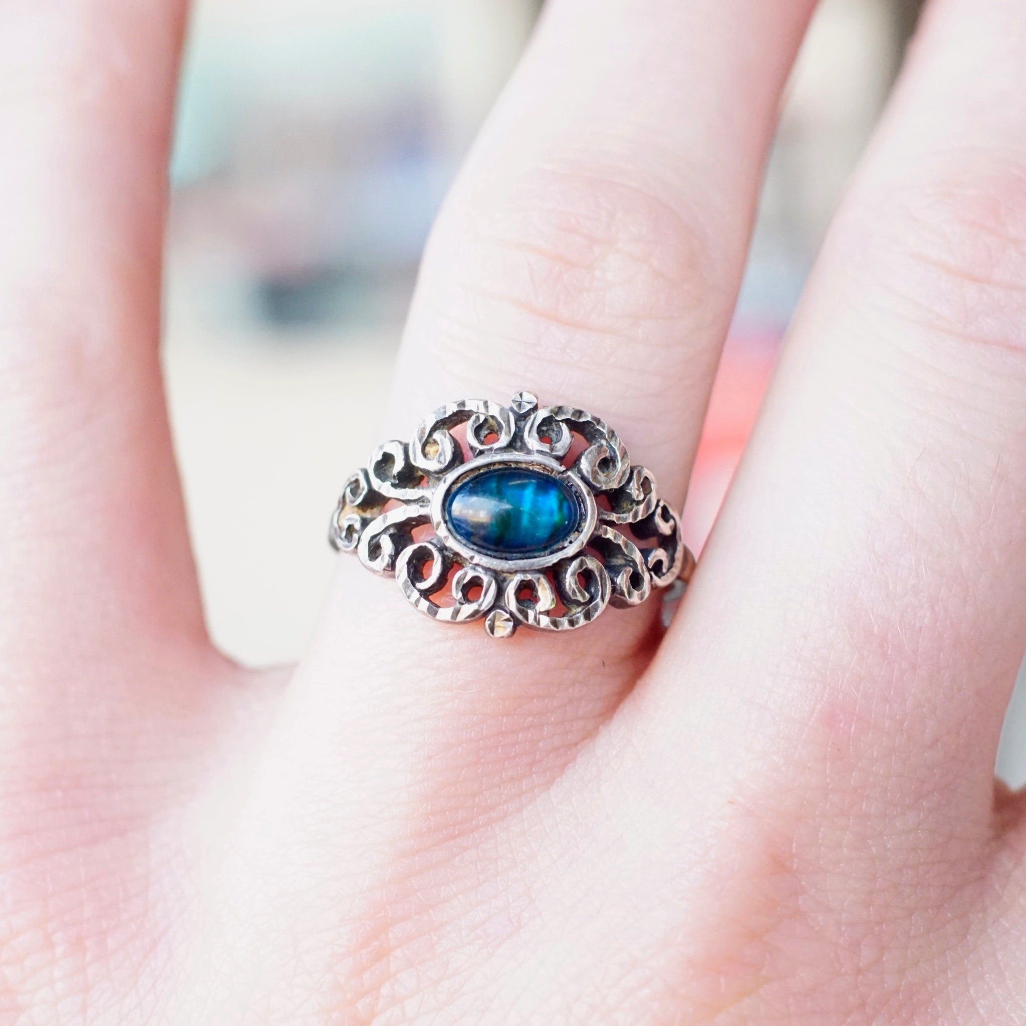Vintage ornate sterling silver ring with iridescent blue glass stone, hammered and textured silver design, size 9 1/4 US, shown on model's hand.