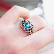 Vintage ornate sterling silver ring featuring an iridescent blue glass stone set in an intricate textured and hammered silver design. The ring is a US size 9 1/4.