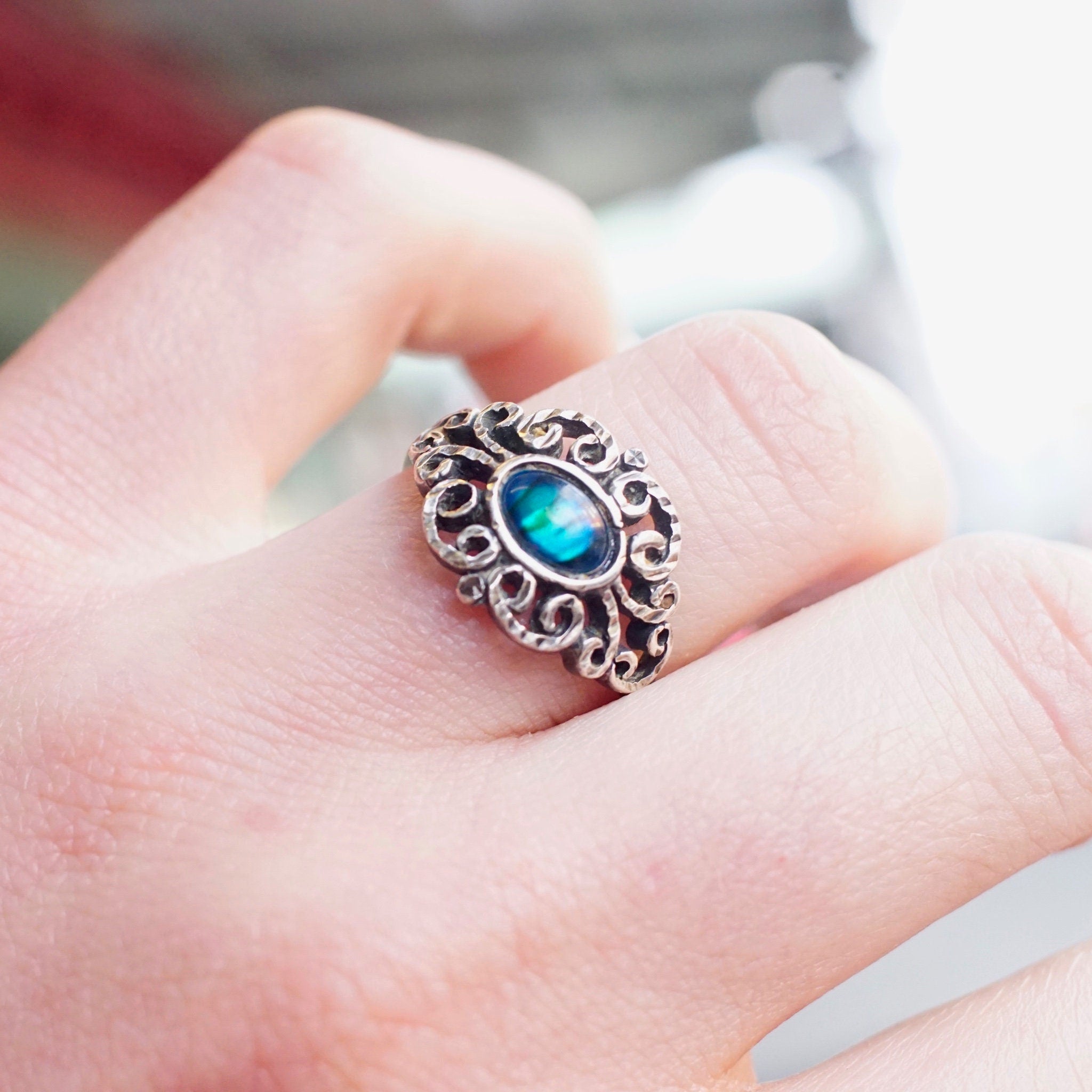 Vintage ornate sterling silver ring featuring an iridescent blue glass stone set in an intricate textured and hammered silver design. The ring is a US size 9 1/4.