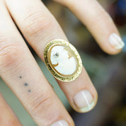 Vintage 14K gold cameo ring with ornate setting and accent diamond, showcasing an intricately carved shell cameo on a woman's hand, ring size 3 3/4 US.
