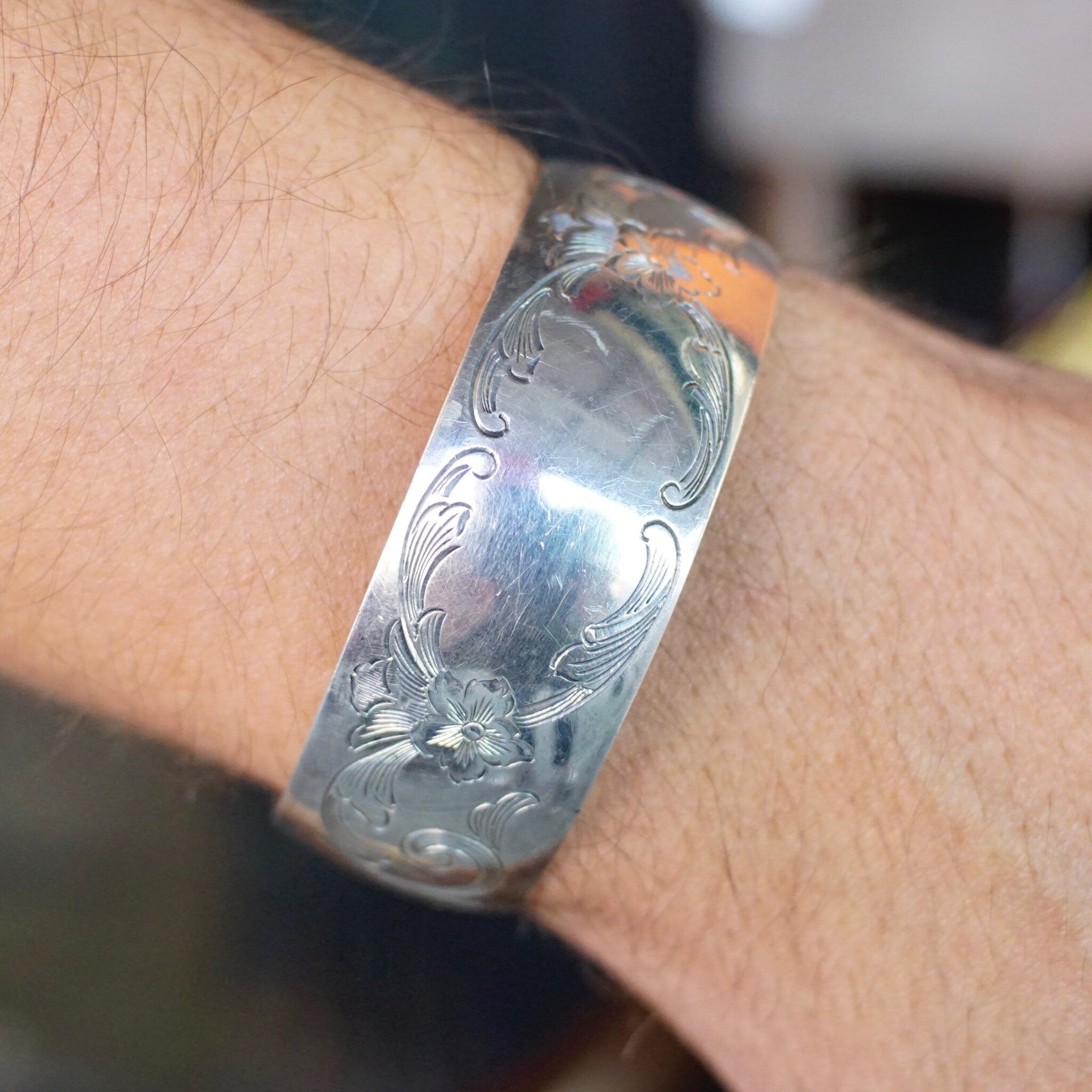 Vintage S. Kirk & Son sterling silver cuff bracelet with etched floral design, space for engraved monogram on the polished center section, shown on a person's wrist.