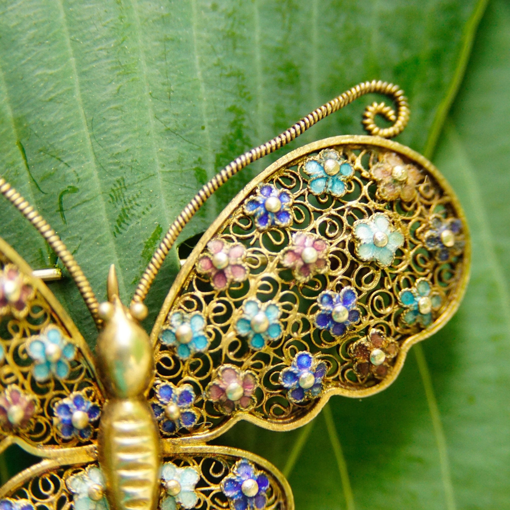 Antique Chinese silver filigree butterfly brooch with gold wash, featuring hand-carved nephrite jade, intricate enamel work, and a delicate wedding basket design, showcasing the artisan craftsmanship of devil's work metalwork technique.