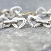 Vintage Tiffany & Co 18K gold and sterling silver heart link bracelet, curb chain design, measuring 7 1/2 inches long, close-up view on gray background
