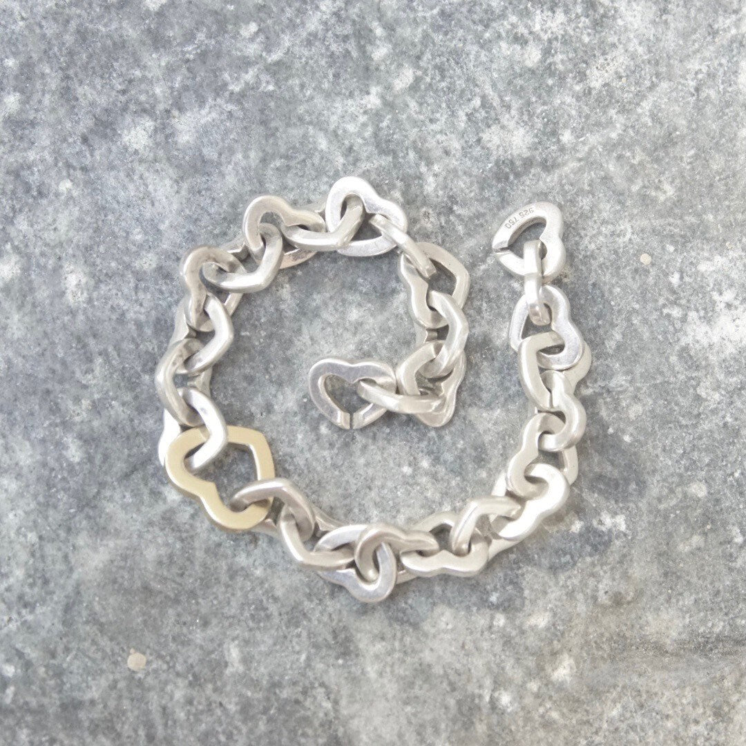Vintage Tiffany & Co. two-tone heart link bracelet crafted in 18K gold and sterling silver, featuring interlocking hearts in an elegant curb link design, measuring 7 1/2 inches in length.