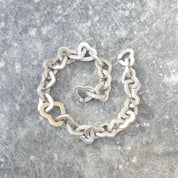 Vintage Tiffany & Co. two-tone heart link bracelet crafted in 18K gold and sterling silver, featuring interlocking hearts in an elegant curb link design, measuring 7 1/2 inches in length.