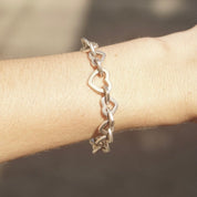 Tiffany & Co. two-tone heart link bracelet in 18K gold and sterling silver on wrist, close-up view of vintage curb chain jewelry piece with alternating gold and silver heart-shaped links, 7 1/2 inches long.