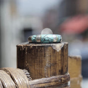 Vintage sterling silver tapered band ring with light blue speckled turquoise inlay, stacked on weathered wooden surface, selective focus