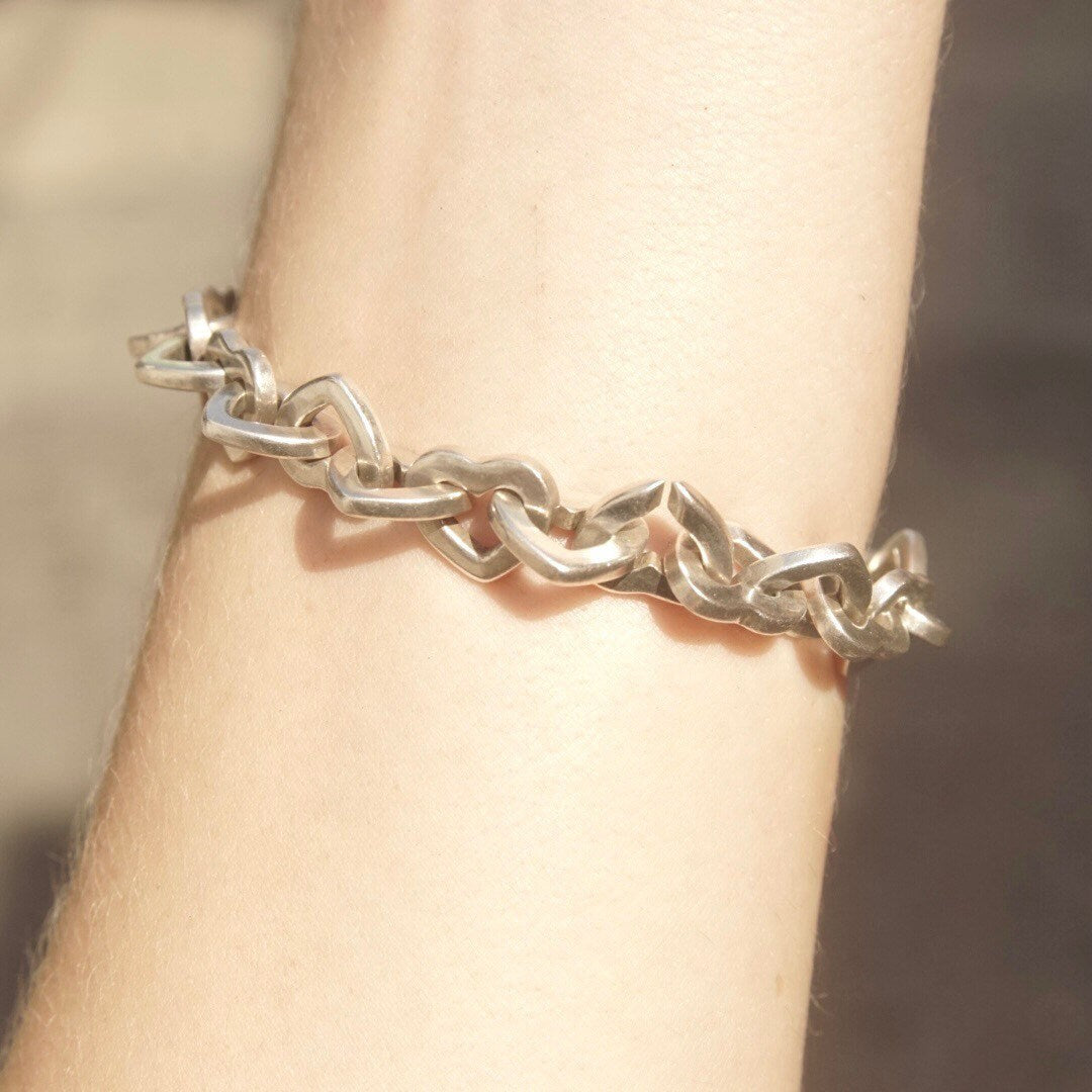 18K gold and sterling silver heart link bracelet from Tiffany & Co, featuring two-tone curb links. Vintage Tiffany jewelry, measuring 7 1/2 inches long.