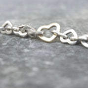 Vintage Tiffany & Co. sterling silver heart link bracelet with alternating 18K gold heart links, close-up view on gray background