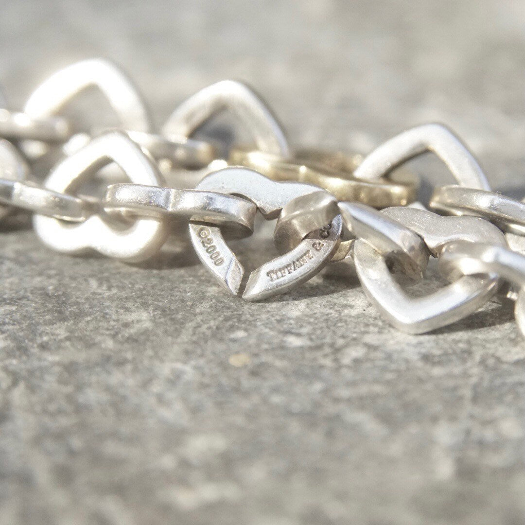 Vintage Tiffany & Co. two-tone 18K gold and sterling silver heart link bracelet, close-up view on textured gray background