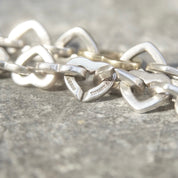 Vintage Tiffany & Co. two-tone 18K gold and sterling silver heart link bracelet, close-up view on textured gray background
