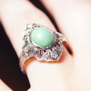 Vintage 18K white gold Art Deco filigree ring with matte green turquoise stone and diamond encrusted shield design, size 7 3/4 US, shown on finger