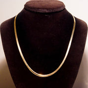 Vintage 14K yellow gold herringbone chain necklace displayed on black velvet bust, showing elegant minimalist design with 3mm flat herringbone links and 20 inch length, suitable as unisex jewelry piece.