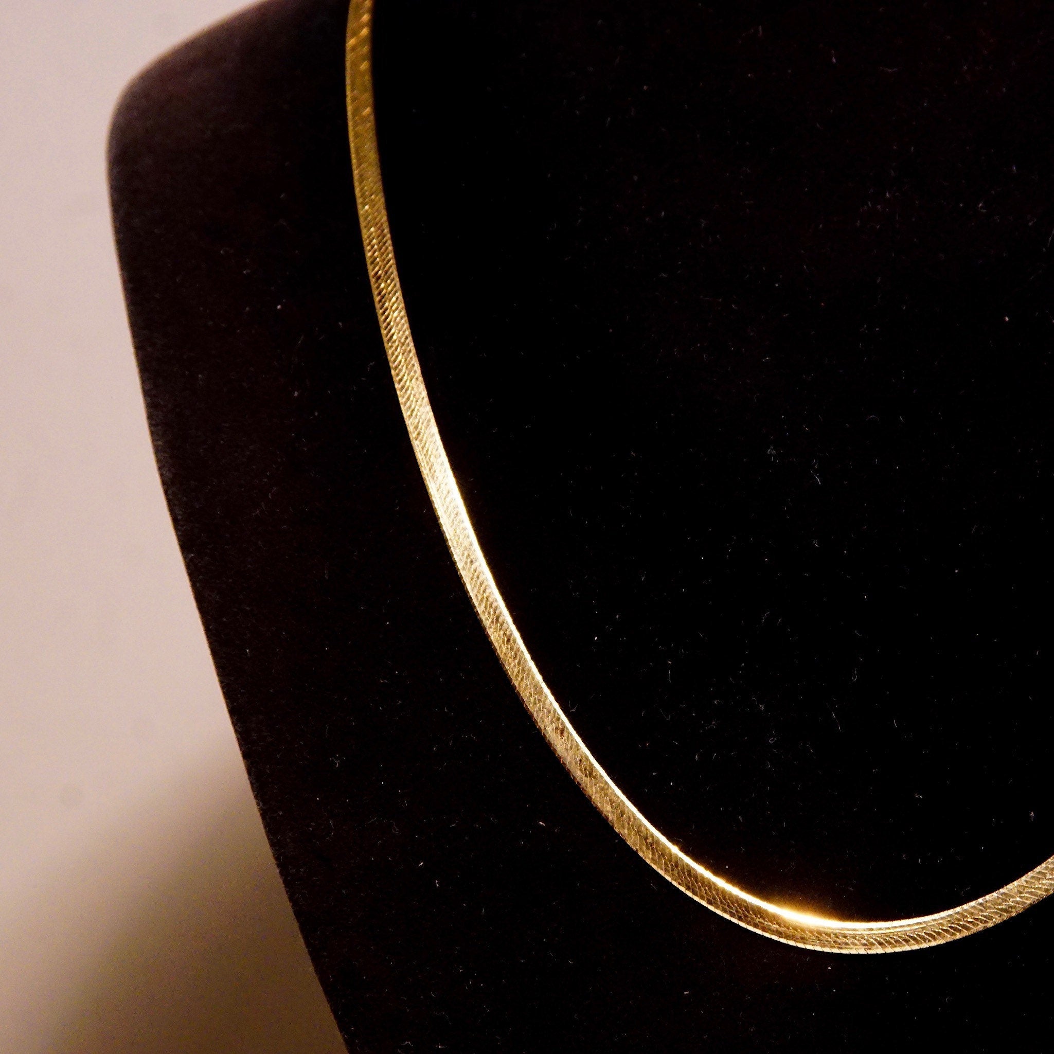Vintage 14K yellow gold herringbone chain necklace on black velvet display, showing flat 3mm chain links and delicate gold shimmer, unisex minimalist Italian gold jewelry, 20 inches long.