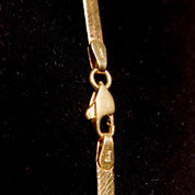 Vintage 14K yellow gold herringbone chain necklace, 3mm wide flat links, 20 inches long, minimalist unisex design, close-up view on black background.