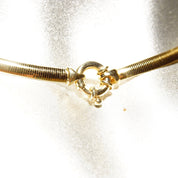 Vintage Italian 14K yellow gold omega collar necklace with minimalist design, 4mm thick, lustrous finish, made in Italy, 585 stamped, 16 inches long, closeup view on shimmery background.