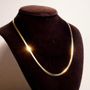 Vintage 14K yellow gold herringbone chain necklace on black velvet bust display, showing elegant minimalist design of flat 3mm wide chain links, 20 inches long, suitable as unisex jewelry piece.