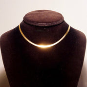 Vintage 14K yellow gold Italian herringbone chain necklace on black velvet bust display, showing the minimalist flat chain design and warm golden glow against the dark background.