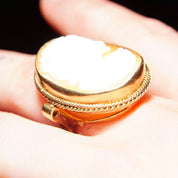 Ornate Victorian 10K yellow gold ring with a large classic relief cameo set in an intricate scrollwork gold setting, size 7 1/2 US, held in a person's hand.