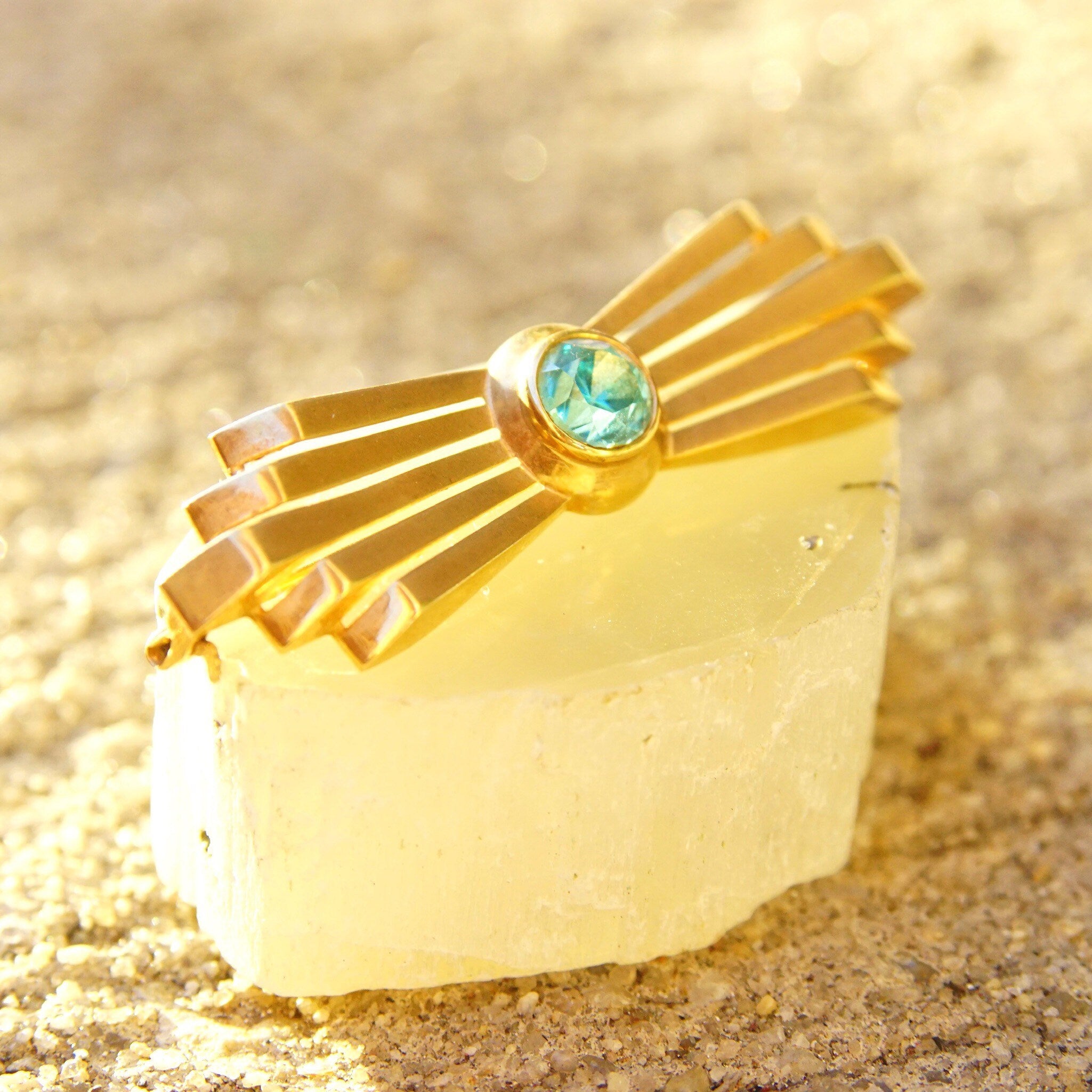 Vintage 14K rose gold Art Deco bar brooch featuring a brilliant blue aquamarine gemstone set in a golden ray design, measuring 2 inches long.