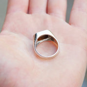 Vintage sterling silver signet ring with iridescent abalone shell inlay, placed in an open palm, showcasing the unisex jewelry design in a men's size 9 1/2 US.