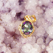 Vintage 14K yellow gold ornate pendant featuring a 26mm x 13mm faceted mystic fire topaz gemstone with iridescent purple and green hues, adorned with a stylized decorative necklace bail.