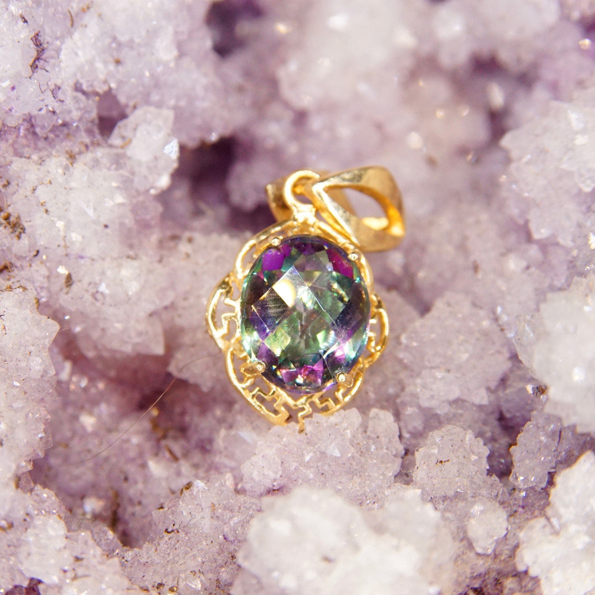 Vintage 14K yellow gold ornate pendant featuring a 26mm x 13mm faceted mystic fire topaz gemstone with iridescent purple and green hues, adorned with a stylized decorative necklace bail.
